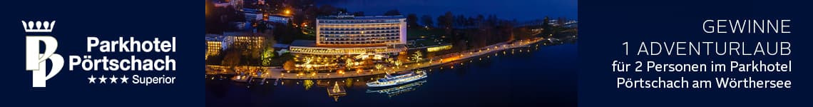 Gewinne 1 Adventurlaub für 2 Personen im Parkhotel Pörtschach am Wörthersee – beleuchtetes Hotel und Boot bei Nacht