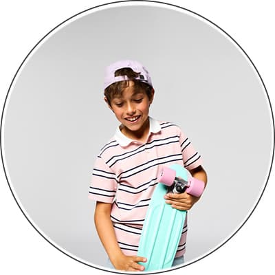 Kind mit rosa gestreiftem T-Shirt und helllila Baseballkappe hält ein türkises Skateboard mit pinken Rollen