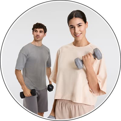 Zwei Personen beim Workout – Frau hebt Hantel in beigeem Shirt, Mann hebt Hantel in grauem Shirt und Shorts