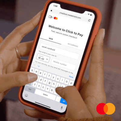 Welcome to Click to Pay – Hände halten Smartphone mit Mastercard-Checkout-Seite, Nutzerin gibt Kartendaten ein