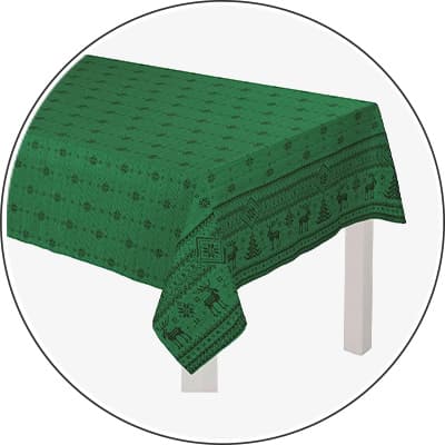 Grüne Tischdecke mit weihnachtlichem Muster aus Tannenbäumen und Rentieren auf weißem Tisch ausgebreitet