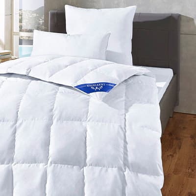 Schlafzimmer mit weißer Bettdecke und Kissen auf einem grauen Bett