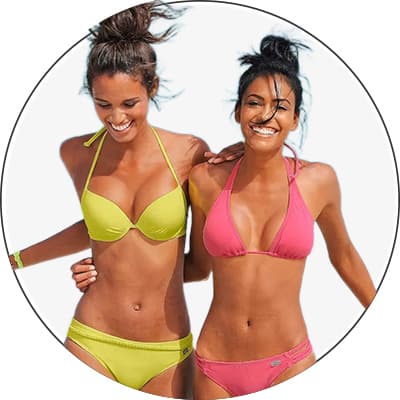 Zwei Frauen in gelbem und pinkem Bikini stehen nebeneinander und posieren vor hellem Hintergrund