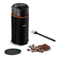 Schwarze elektrische Kaffeemühle mit Deckel, Pinsel, Kaffeebohnen und gemahlenem Kaffee auf weißem Hintergrund