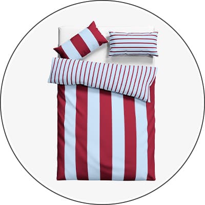 Bett mit rot-weiß gestreifter Bettwäsche, Decke und zwei Kissen von oben gesehen