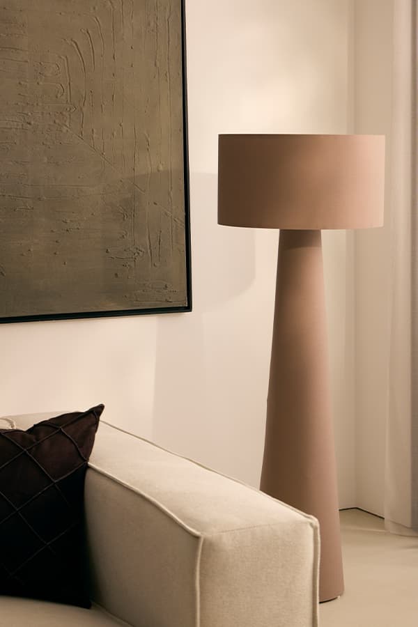 Beige Stehleuchte mit breitem Schirm neben hellem Sofa und großem abstraktem Wandbild