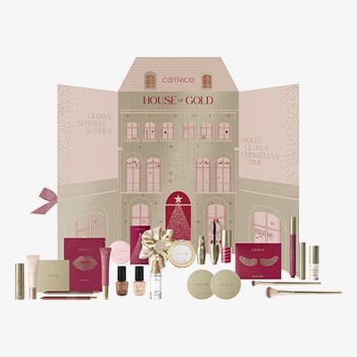 CATRICE House of Gold Adventskalender mit aufgeklappter Hauskulisse und davor arrangierten Make-up-Produkten