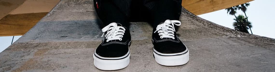 Ein Paar schwarze Vans auf grauem Beton