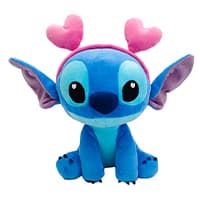 Blaue Plüschfigur mit großen Augen und rosa Herz-Antenne auf dem Kopf, sitzt und schaut geradeaus