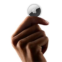 Hand hält einen kleinen kreisförmigen Apple AirTag zwischen Daumen und Zeigefinger vor weißem Hintergrund.