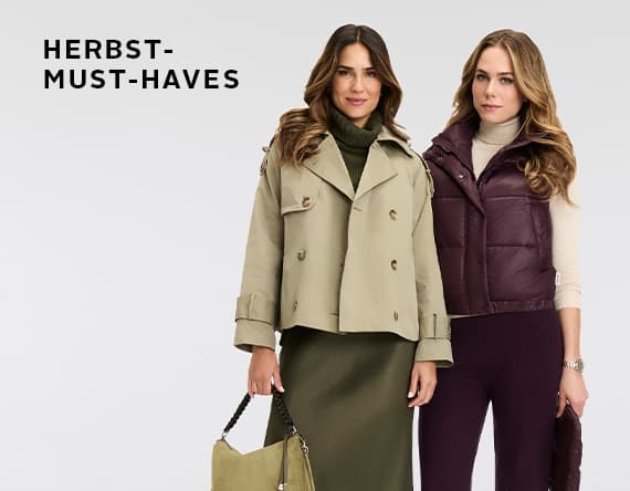HERBST-MUST-HAVES – Zwei Frauen tragen Herbstmode. Eine in khakigrüner Jacke und Rock, die andere in lila Weste und Hose.