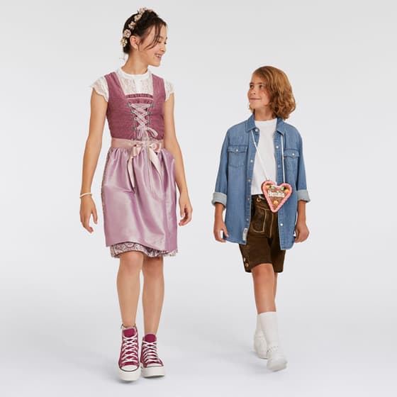 Kind in rosa Dirndl und Kind in Lederhose mit Lebkuchenherz "Herzilein" – traditionelle bayerische Kleidung