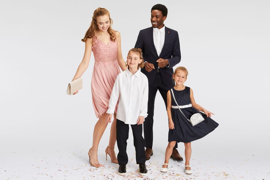 Vierköpfige Familie in festlicher Kleidung, Eltern in Anzug und Kleid, Kinder in Hemd und Kleid, auf weißem Hintergrund mit Konfetti