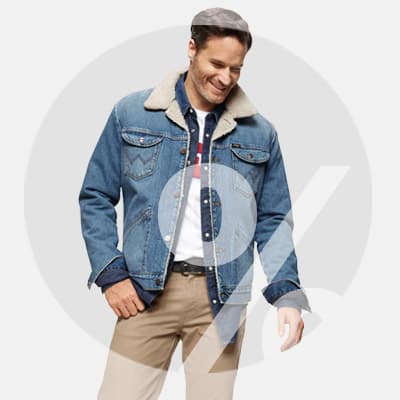 Mann trägt blaue Jeansjacke mit Fellkragen, weißes T-Shirt und beigefarbene Hose