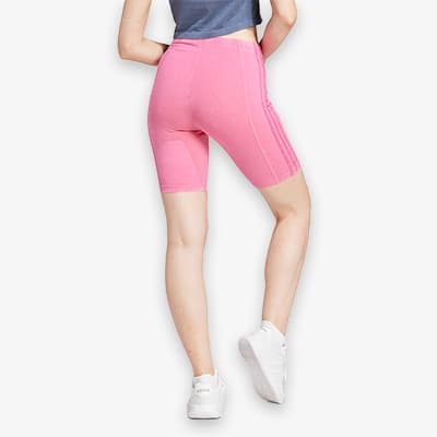 Frau in pinken Radlerhosen und weißem Sneaker zeigt Rückenansicht, hebt ein Bein leicht an