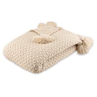 Beige gestrickte Decke mit Zopfmuster und Quasten an den Ecken, zusammengefaltet auf weißem Hintergrund