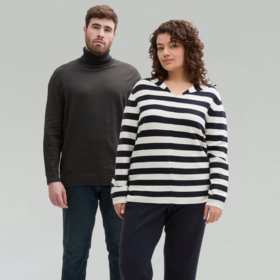 Mann in grauem Rollkragenpullover und Jeans, Frau in schwarz-weiß gestreiftem Pullover und dunkler Hose, beide mit verschwommenen Gesichtern.