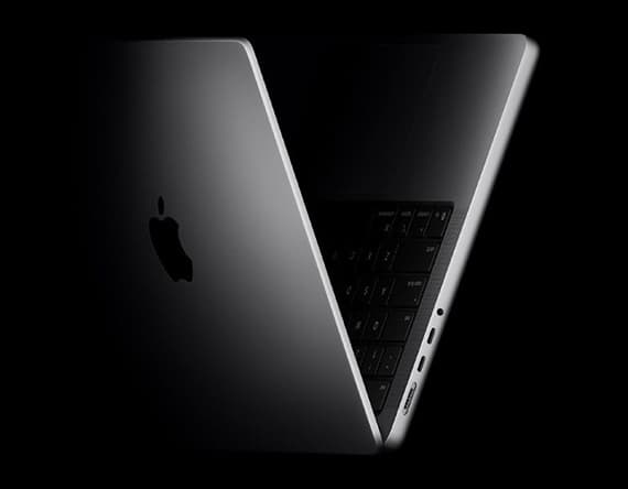 Teilweise geöffneter silberner Laptop mit Apple-Logo, beleuchtete Tastatur und mehrere Anschlüsse sichtbar