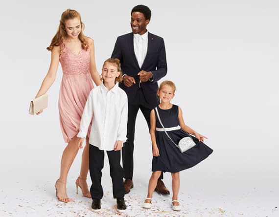 Vier Personen in festlicher Kleidung – Frau im rosa Kleid, Mann im Anzug, Junge in weißem Hemd, Mädchen im blauen Kleid