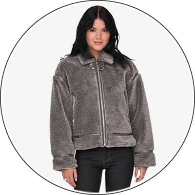 Frau trägt graue, flauschige Jacke mit Reißverschluss und Kragen, schwarze Hose