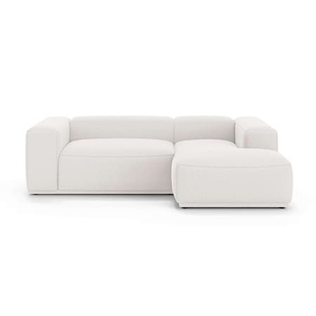 Modernes weißes Sofa mit L-förmiger Ottomane, breiten Armlehnen und tiefem Sitz, auf weißem Hintergrund.