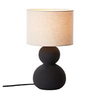 Schwarze Tischlampe mit beigem Lampenschirm und rundem Sockel, eingeschaltet mit Kabel auf weißem Hintergrund