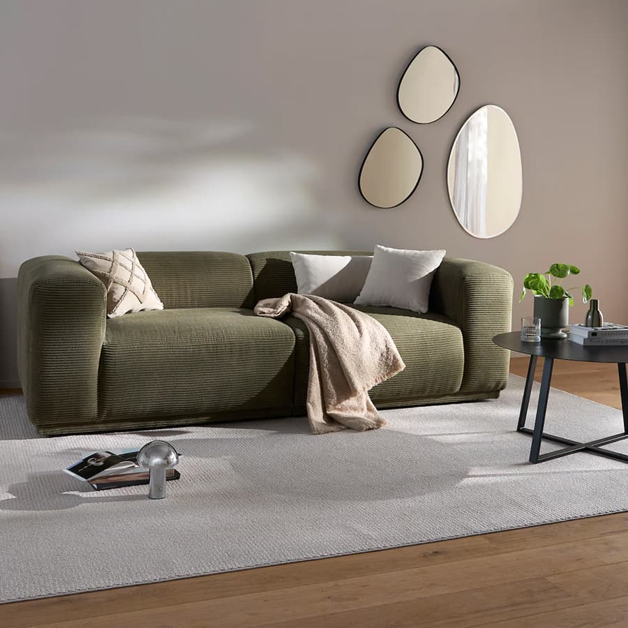 s.Oliver Fußmatten in verschiedenen Farben und Formen auf grauem Boden, daneben Holztisch mit Dekorationen