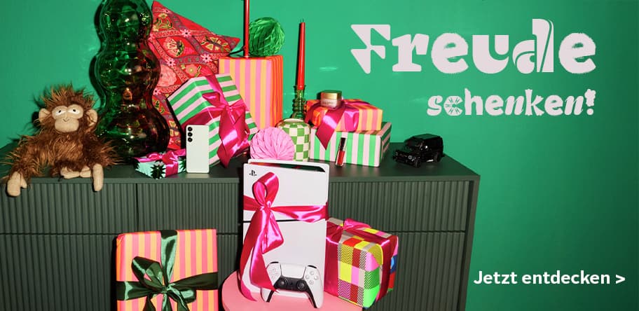 Freude schenken! Jetzt entdecken > – Verschiedene bunte Geschenke, PlayStation 5, Spielzeugauto und Plüschaffe auf Kommode