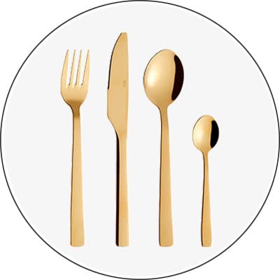 Goldfarbenes Besteckset bestehend aus Gabel, Messer, Löffel und Teelöffel auf weißem Hintergrund