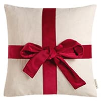 Quadratisches Kissen mit roter Schleife und Band in Geschenkoptik auf weißem Hintergrund