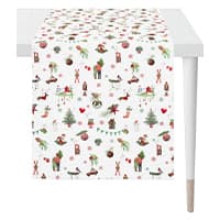 Tischläufer mit bunten Weihnachtsmotiven auf weißem Hintergrund, ausgebreitet auf einem weißen Tisch