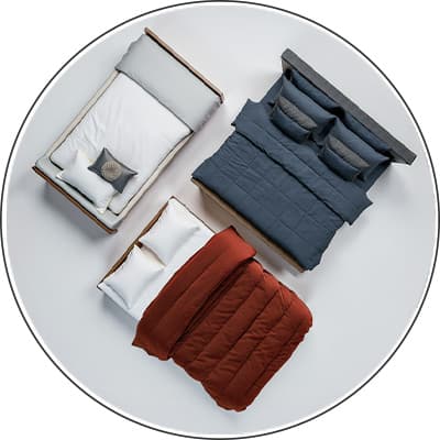 Drei Betten von oben – links graue Decke, Mitte blaue Decke mit Kissen, rechts rote Decke mit weißen Kissen