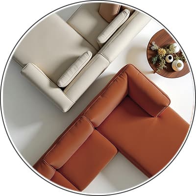 Zwei Sofas aus Vogelperspektive, eins beige und das andere braun, daneben runder Holztisch mit Vasen und Blumenarrangement