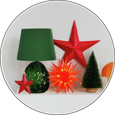 Grüne Tischlampe, roter Stern, kleine rote Stern-Deko, leuchtender orangefarbener Stern und kleiner künstlicher Tannenbaum