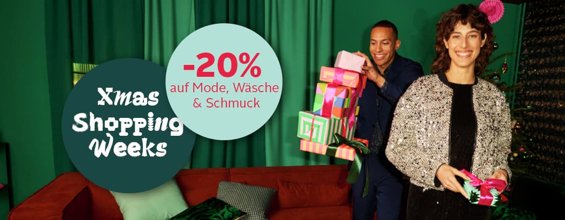 -20 % auf Mode, Wäsche & Schmuck – Frau mit silberner Jacke und Mann in blauem Anzug tragen Geschenke vor grünem Hintergrund