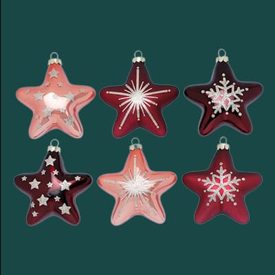 Sechs sternförmige Weihnachtsbaum-Anhänger in Rot und Rosa mit verschiedenen weißen Verzierungen auf grünem Hintergrund