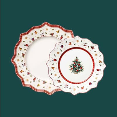 Zwei Weihnachtsteller mit Zackenrand, einer mit Weihnachtsbaum, der andere mit bunten Weihnachtsmotiven und rotem Rand