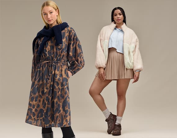 Zwei Frauen in modischer Kleidung – links in langem gemusterten Mantel, rechts in kurzem Rock, Bluse und heller Jacke