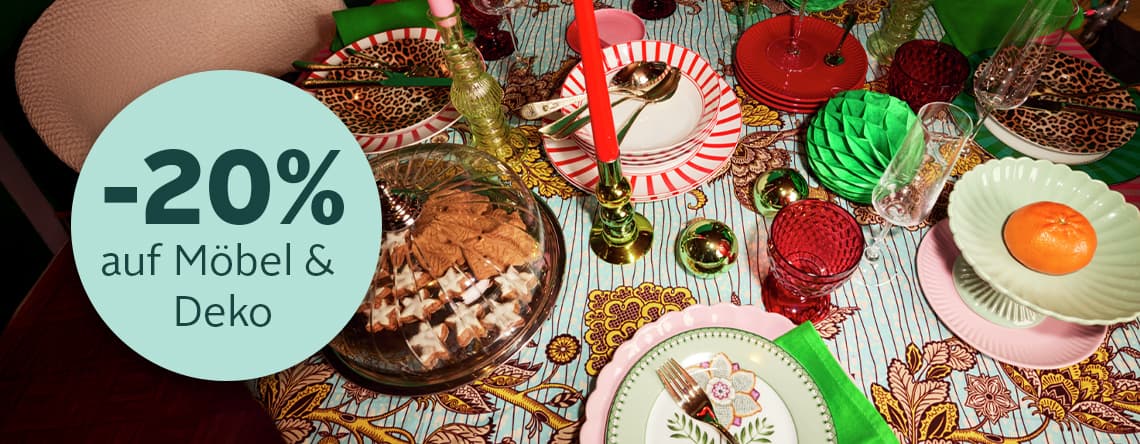 -20% auf Möbel & Deko – Bunt gedeckter Tisch mit verschiedenen Tellern, Gläsern, Besteck und Gebäck in einer Glasglocke