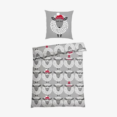Bettwäsche-Set mit Schaf-Motiv und roter Mütze auf grauem Hintergrund.
