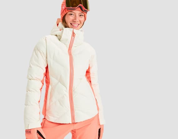 Person in weißer und korallfarbener Winterjacke mit passender Hose und Mütze.