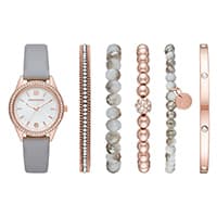 Armbanduhr mit grauem Band und fünf dazu passende Armbänder in Roségold und Weiß.