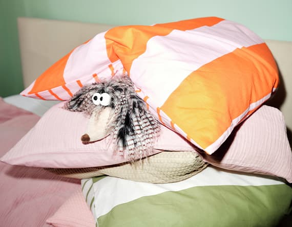 Stofftier zwischen bunten Kissen auf einem Bett