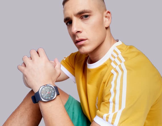 Mann in gelbem T-Shirt mit weißen Streifen trägt eine große Uhr mit dunklem Armband.