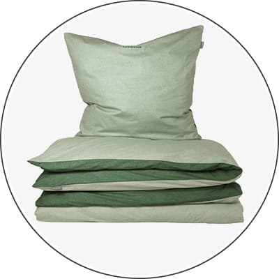 Grünes Bettwäsche-Set bestehend aus Kopfkissen und gefaltetem Bettbezug.