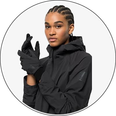 Person in schwarzer Jacke und Handschuhen zieht sich die Handschuhe an