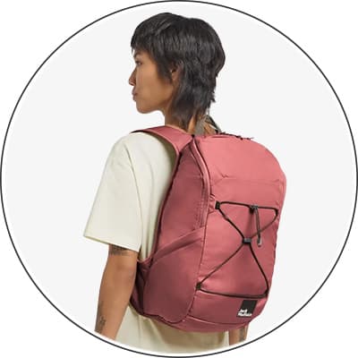 Person trägt roten Rucksack mit schwarzen Schnürdetails über weißem T-Shirt.