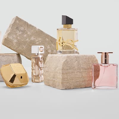 Verschiedene Parfümflaschen auf und zwischen Steinblöcken arrangiert.