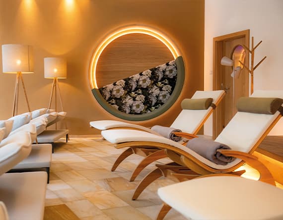 Entspannungsraum mit Liegestühlen und rundem, beleuchtetem Wanddekor mit Blumenmuster.