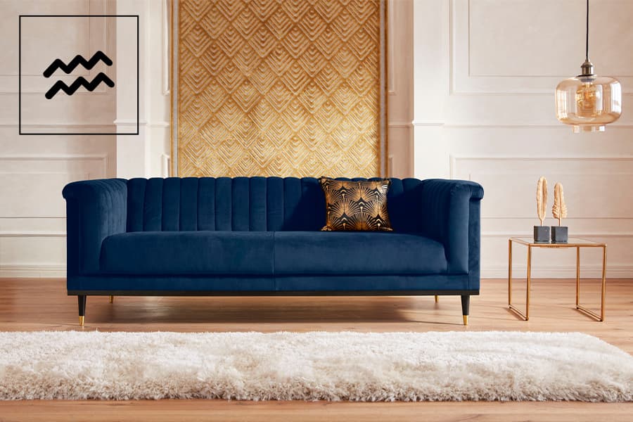 Elegantes Wohnzimmer mit dunkelblauem Sofa, goldener Kissen und modernem Beistelltisch vor gemusterter Tapete.